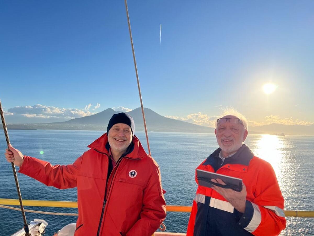 Alla scoperta del mantello del Tirreno: nuove rivelazioni sulla formazione degli oceani - Expedition 402 Co-Chief Scientists Alberto Malinverno (Lamont-Doherty Earth Observatory, Columbia University, USA), left, and Nevio Zitellini (ISMAR-CNR, Italy), right, smile for a photo during departure with Mt. Vesuvio in the background (Credit: Te